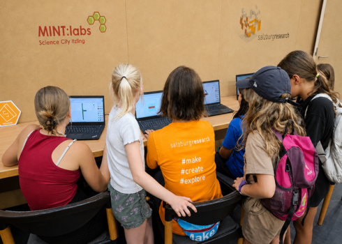 Kinder und Jugendliche arbeiten gemeinsam an mehreren Laptops bei einem 3D-Druck-Workshop der MINT:labs Science City Itzling und Salzburg Research.